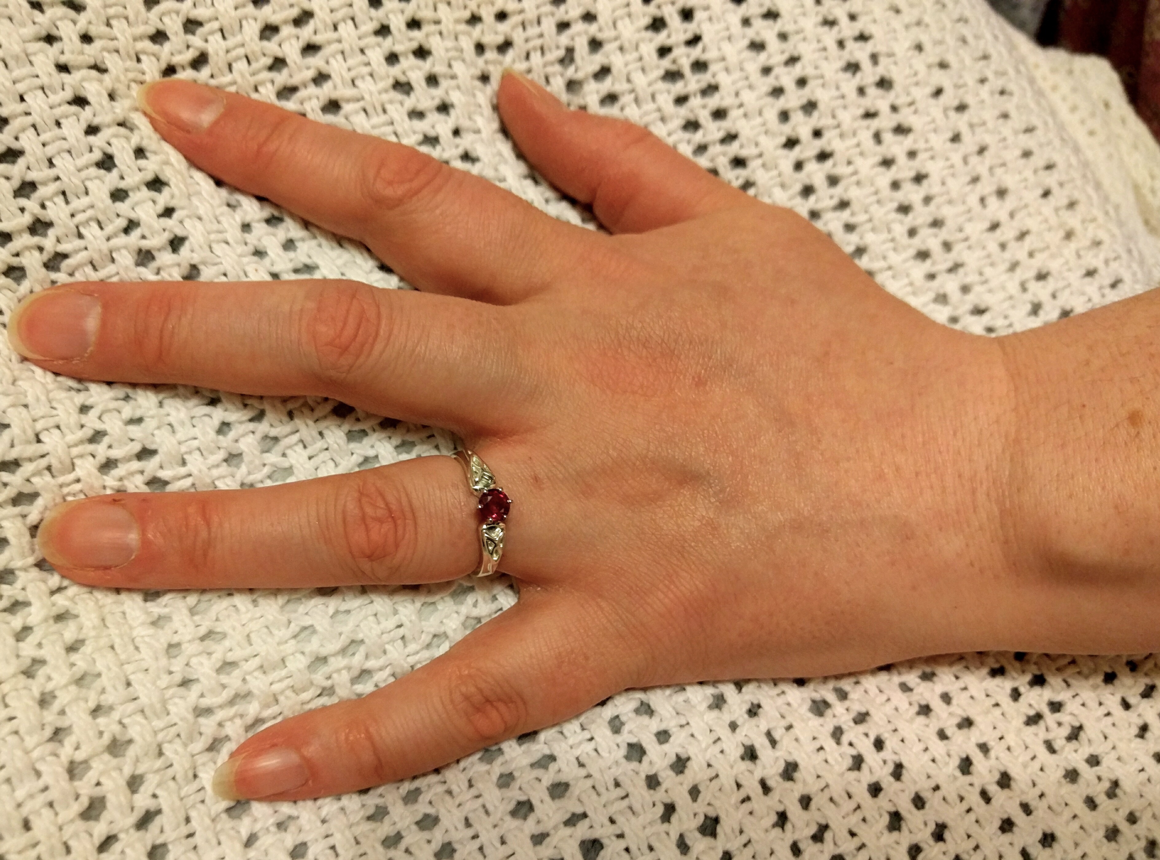 Kerrie's hand wearing ruby engagement ring